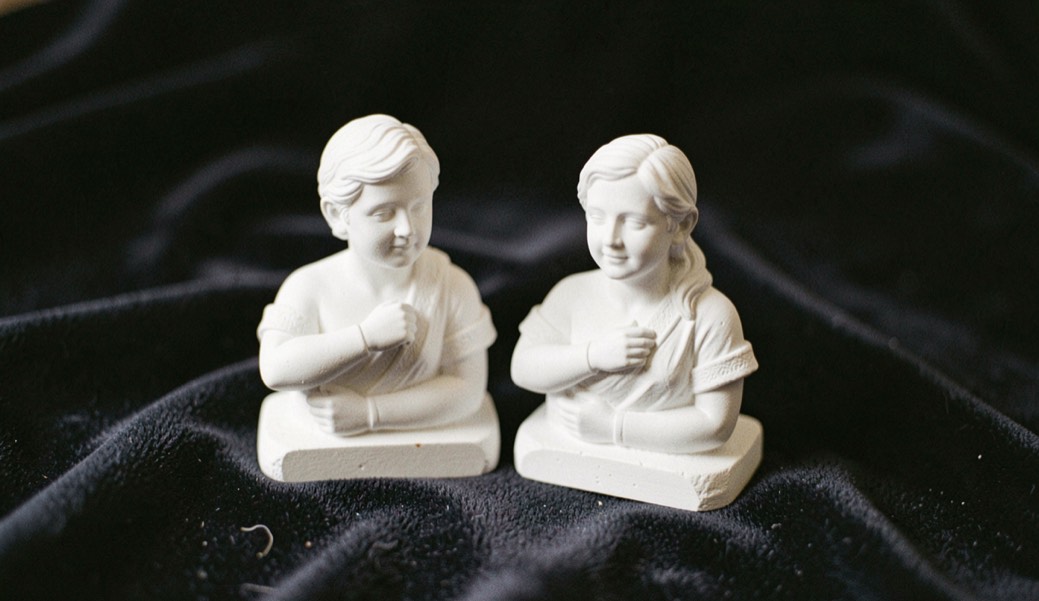 Couple de statuettes en biscuit blanc posées sur un tapis de velours sombre
